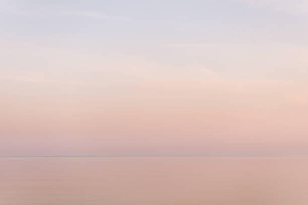 istock Majestic sunset in pastel tones over calm water surface. 963195720
