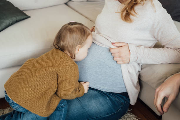 Toddler kissing mom's pregnancy belly