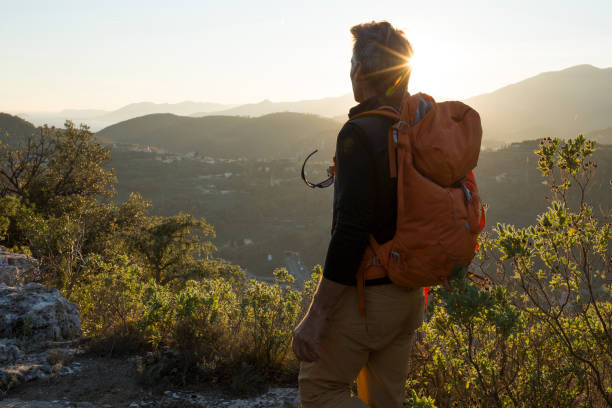 Male hiker wanders through hills in sunlight