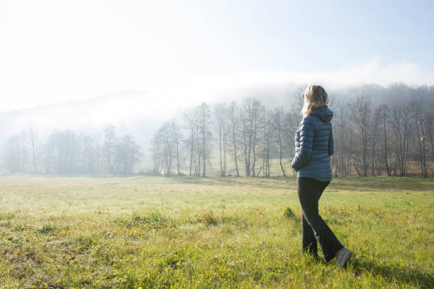 istock Woman walks through hilly meadow in mist 963198060