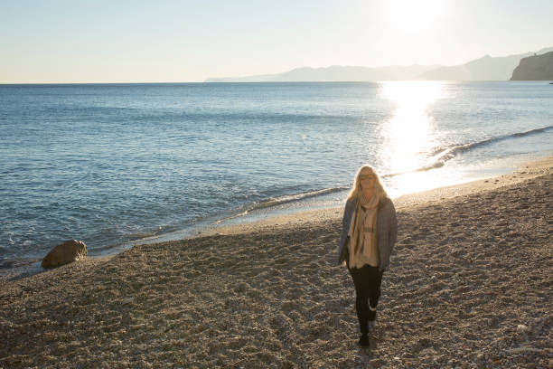 istock Woman walking along beach in sunlight 963198146