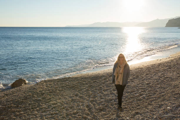 istock Woman walking along beach in sunlight 963198154