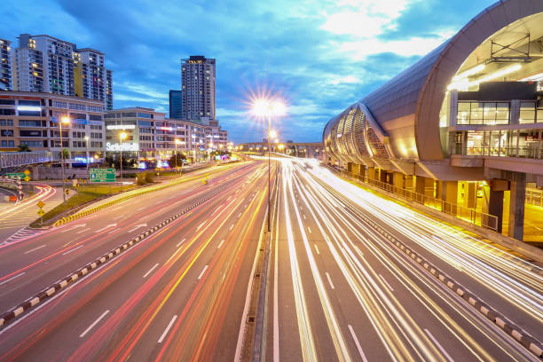 istock Light Trails On Road By Buildings Against Sky At Night 963201080