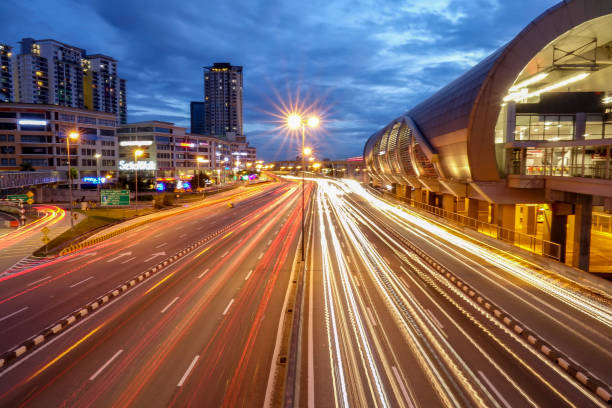 istock Light Trails On Road By Buildings Against Sky At Night 963201256