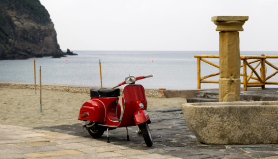 vespa, red scooter and fountain in the beach