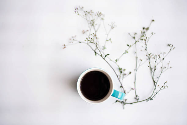 istock The ceramic coffee cup put beside flower,on white background.blurry light around. 963206524