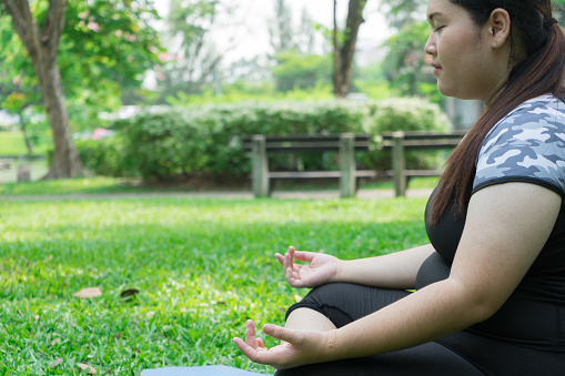 woman practicing yoga and Meditation on green grass in the park. health concept and copy space for text.