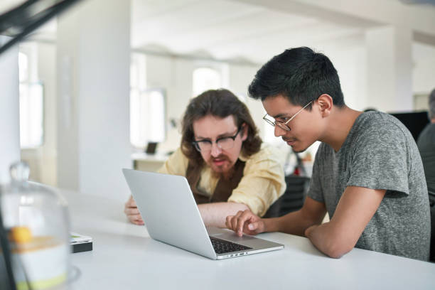 istock Businessmen using laptop at desk in office 963240112