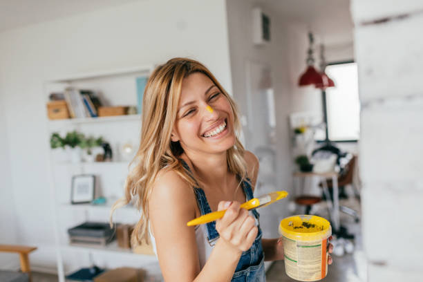 House painting in progress Portrait of a young smiling woman painting her house all by herself diy stock pictures, royalty-free photos & images