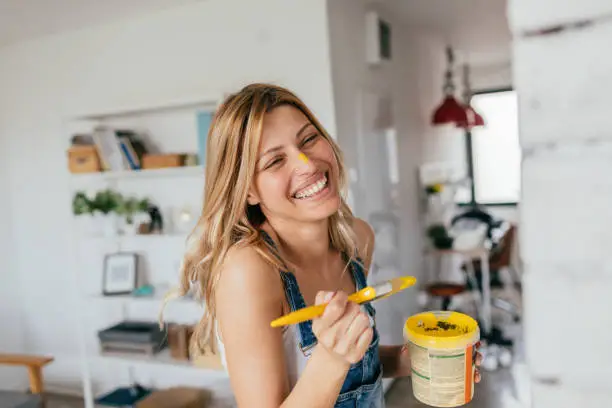 Portrait of a young smiling woman painting her house all by herself