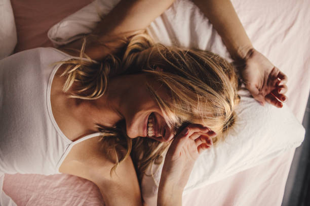 Waking up with happy Portrait of a young beautiful woman waking up, with a smile on her face hair on pillow stock pictures, royalty-free photos & images