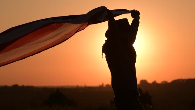 Slow Motion Footage of Caucasian American Cowboy Patriot Running with Flag During 4th of July Independence Day Sunset.