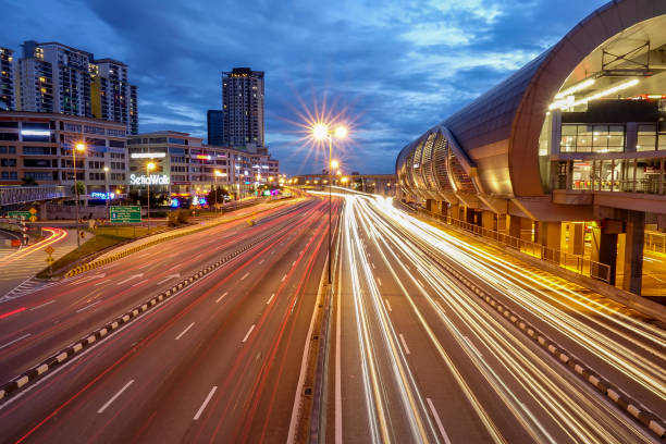 istock Light Trails On Road By Buildings Against Sky At Night 963251320
