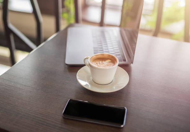 istock Coffee, smartphone and computer on wooden table in restaurant 963283294