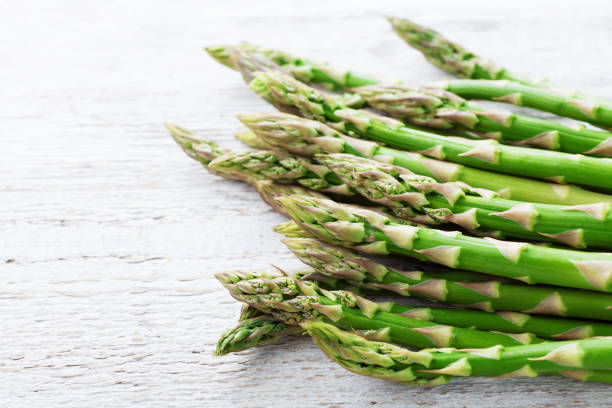 istock Fresh asparagus sprouts on white rustic wooden table. 963287890