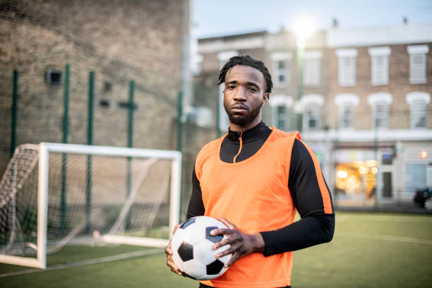 istock Young man holding football and looking towards camera 963295598