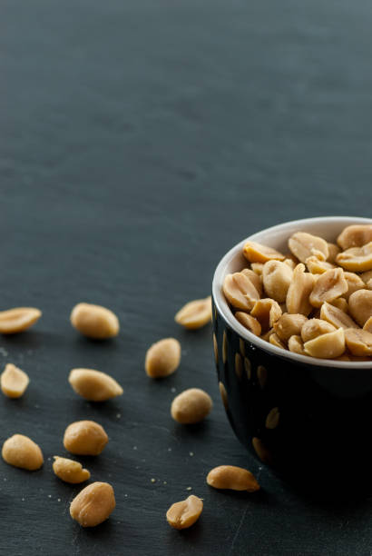 istock bowl with roasted and salted peanuts on a slate with copy space 963299194