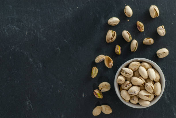 istock bowl with roasted pistachio on a black slate with copy space 963299196