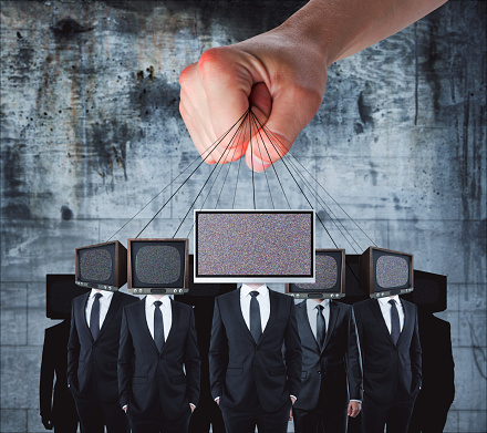 Hand holding TV headed businessmen on rope. Manipulation and brainwash concept