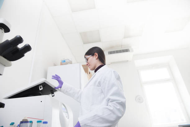 istock Adult Woman Chemist Putting Samples into Centrifugal Separator 963316502