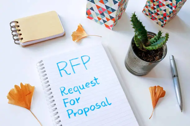 RFP Request For Proposal written in notebook on white table