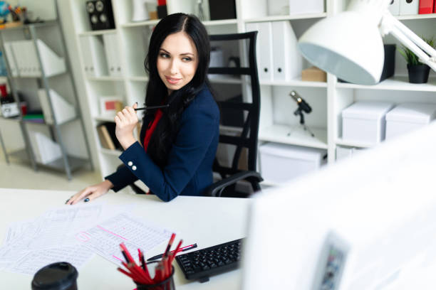 istock Beautiful young girl is looking through documents, sitting in the office at the table. 963350118