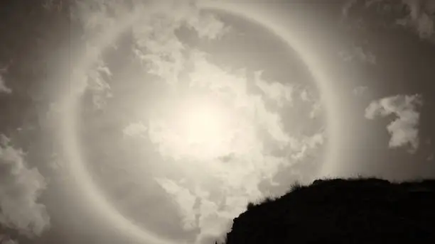 Photo of Sun halo white some rock and tree branches on the sunny day with sepia tone