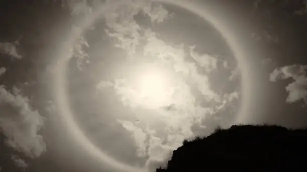 Photo of Sun halo white some rock and tree branches on the sunny day with sepia tone