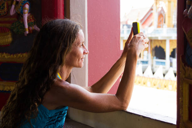 Lady on window taking photographs with cell phone