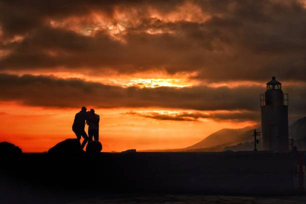 Sunset photo shoot A photographer does a photo shoot of a couple in front of a sunset and lighthouse. kantor stock pictures, royalty-free photos & images