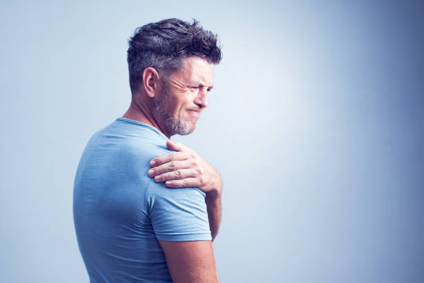 People, healthcare and problem concept - unhappy man suffering from neck or shoulder pain at home People, healthcare and problem concept - unhappy man suffering from neck or shoulder pain at home pain stock pictures, royalty-free photos & images