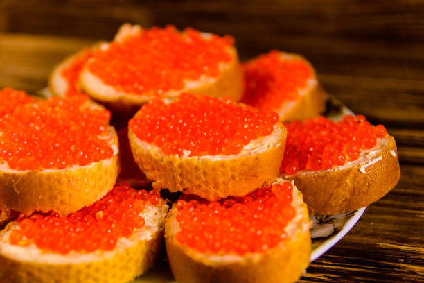 istock Sandwiches with red caviar on wooden table 963391034