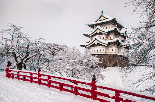 White Hirosaki Castle and its red wooden bridge in mid winter season, Aomori, Tohoku, Japan