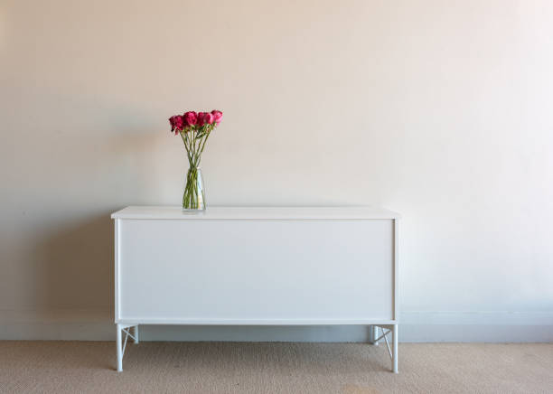 istock Variegated red roses in glass vase on white side table 963395434