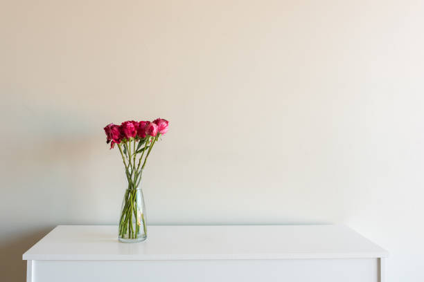 istock Variegated red roses in glass vsae on white sideboard 963395660