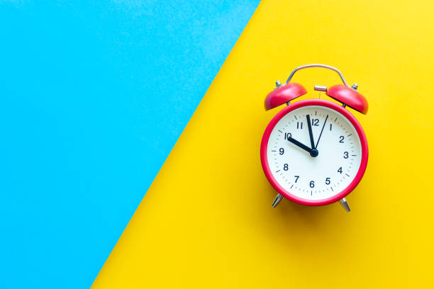 istock A red alarm clock on two tone color yellow and blue background with copyspace 963395988
