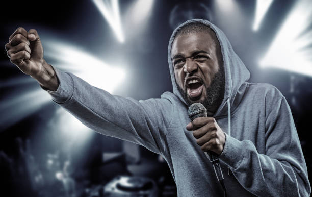 istock Non-Caucasian African emcee rapping into a microphone in front of concert lights 963398416
