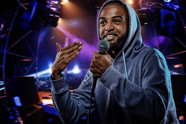 Non-Caucasian African emcee rapping into a microphone in front of concert lights