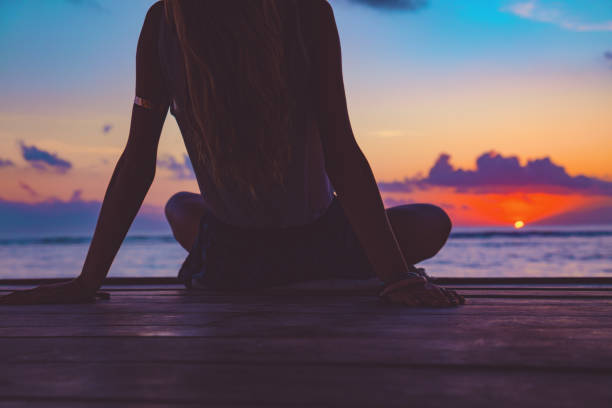 silhouette d’une jeune fille profitant de lever / coucher de soleil sur une pagode de l’océan. - zen like women temple meditating photos et images de collection