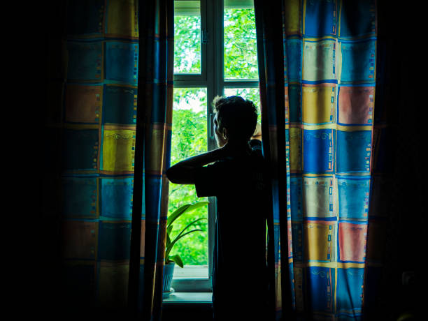 istock alone man silhouette staring at the window closed with curtains in bedroom 963411196