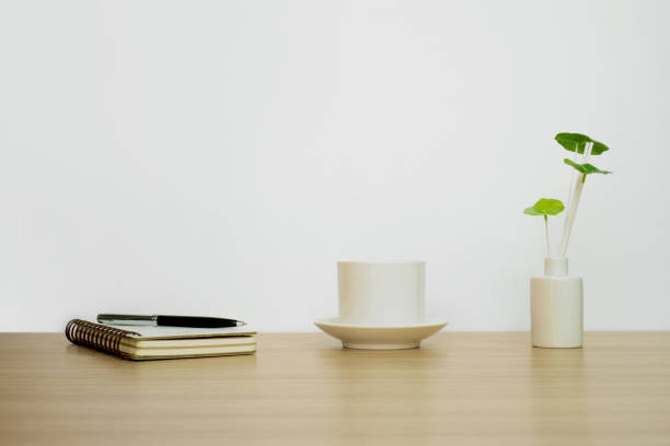 istock Notebook, coffee cup and potted plant on wood table top. 963412262