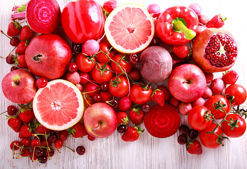 Red color assorted vegetables and fruits on wooden table