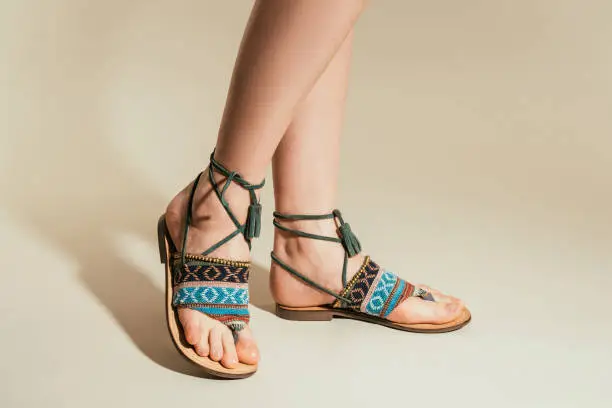 cropped shot of woman legs in stylish sandals on beige background