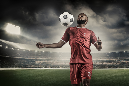 Arabian Muslim Non-Caucasian Football Player controlling a Soccer Ball in a floodlit stadium