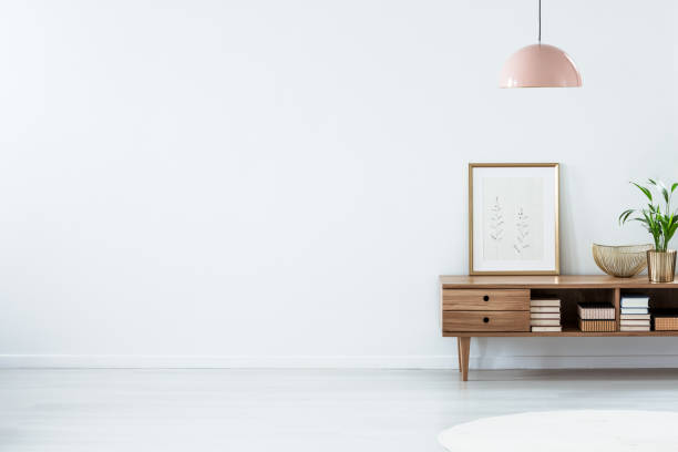 Pink lamp above wooden sideboard Retro pink ceiling lamp above a wooden sideboard in a modern living room interior with an empty white wall and copy space sideboard photos stock pictures, royalty-free photos & images