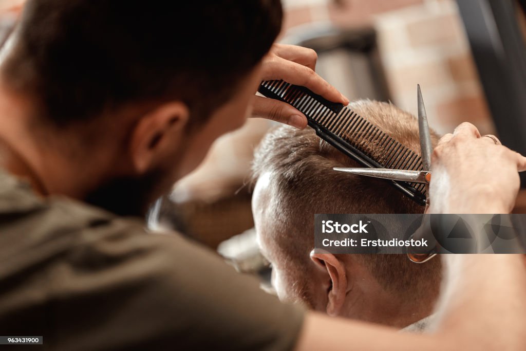 Barber and bearded man in barber shop hairdresser does haircut for bearded man in barber shop Hairdresser Stock Photo