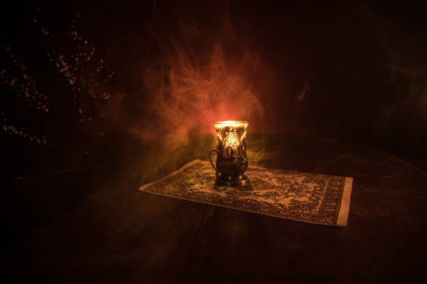 istock Eastern tea in traditional glasse and pot on black background with lights and smoke. Eastern tea concept. Armudu traditional Azerbaijan/Turkish cup 963433352