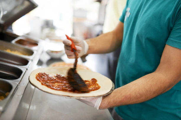 chef puts tomato sauce on pizza workpiece. close-up. - pizza sauces chef making imagens e fotografias de stock