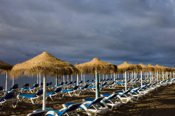 espreguiçadeiras na praia com céu tempestuoso - cloud sea beach umbrella sky - fotografias e filmes do acervo