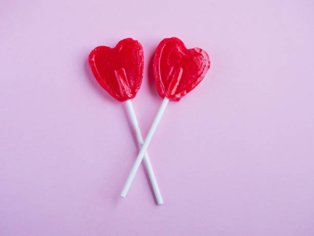 istock Two red heart lollipop on pink background 963437296
